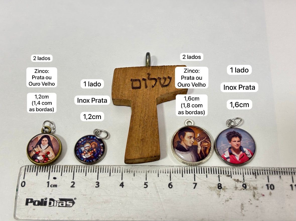 Guia de tamanhos: comparação real das medalhas de 1,2cm e 1,6cm (1 lado) e das medalhas de 2 lados em 1,2cm/1,6cm, ao lado de uma cruz de referência e de uma régua.